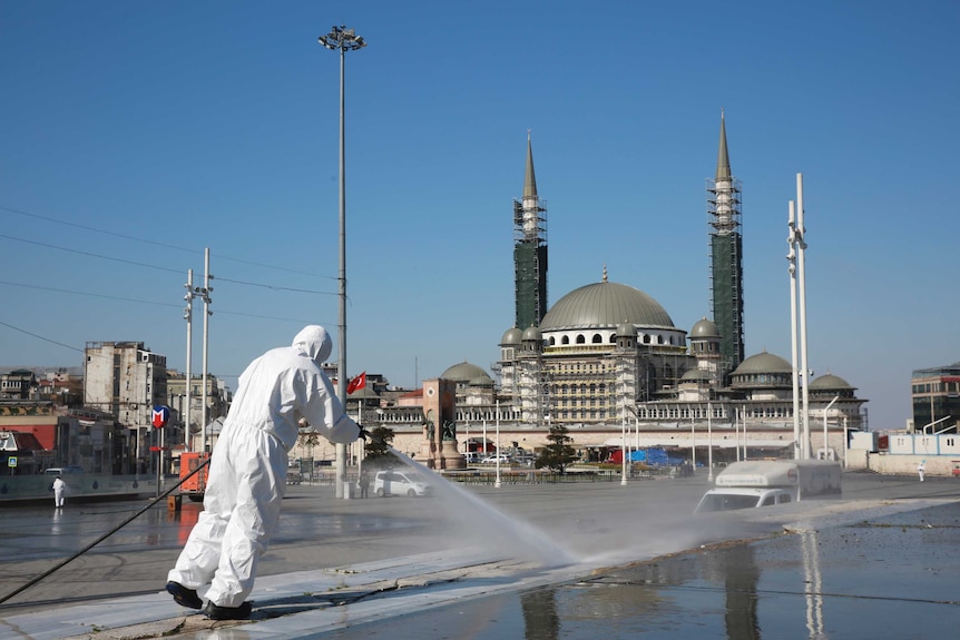Workers clean and disinfect surfaces in front of a mosque in Istanbul's iconic Taksim Square.