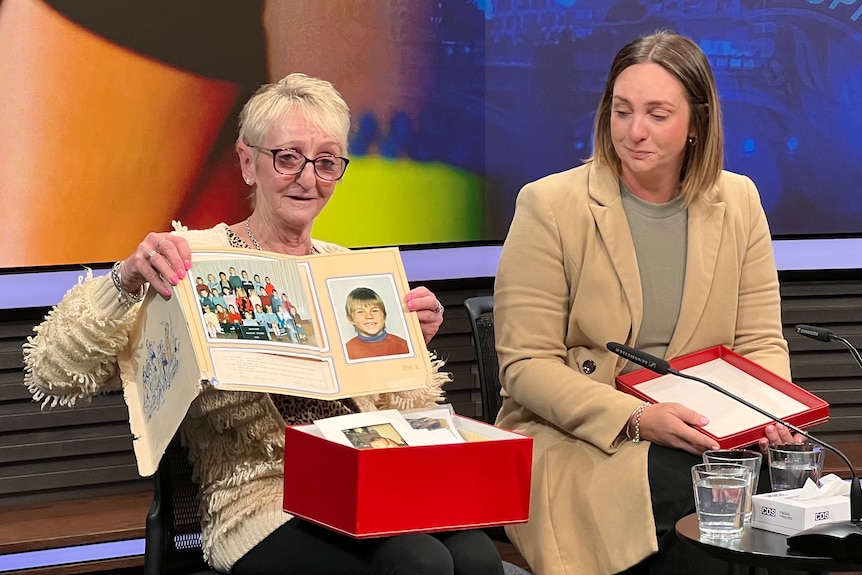 Two women holding a photo. Trevor Tascas's mother Pam and sister Kirsty are calling for the person responsible for his death to come forward.