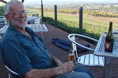 Borry Gartrell sits on his deck drinking a glass of wine and smiling.