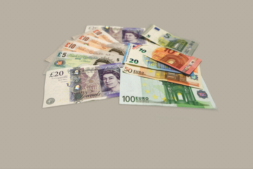 Assorted bank notes are fanned out. Pounds are on the left, Euros are on the right.
