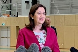 Queensland Premier Annastacia Palaszczuk speaking to the media inside a sports stadium