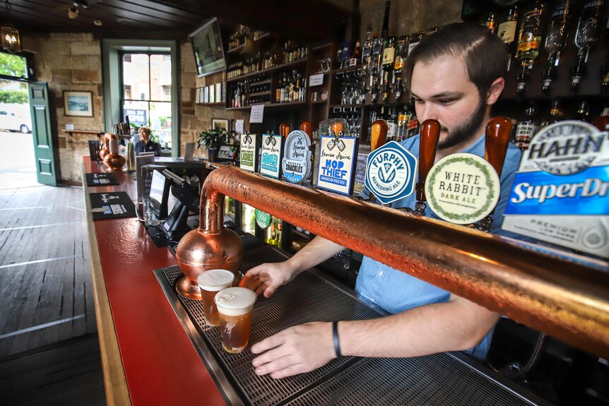 A barman pours beers from taps in an empty bar