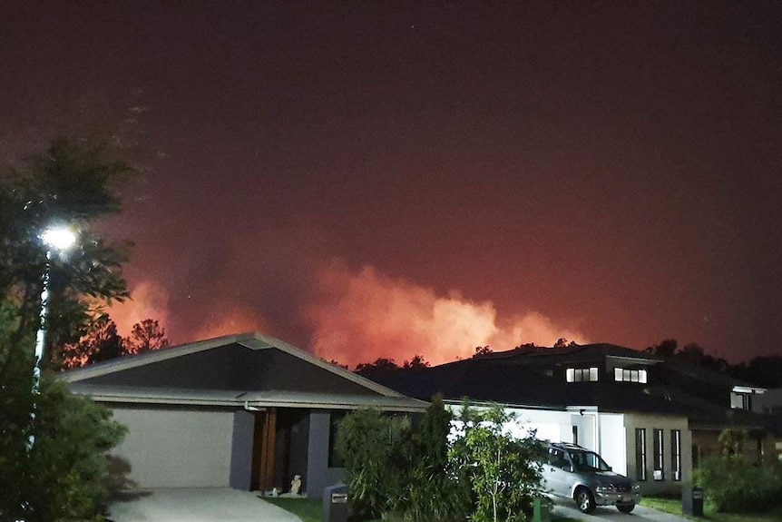 Bushfire burns behind homes at Peregian Springs at night.