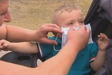 A mother puts a mask on her young son in Morwell to protect him from smoke pollution from the Hazelwood mine fire.
