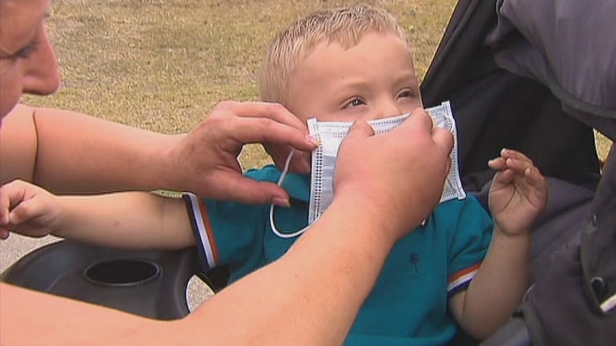 A mother puts a mask on her young son in Morwell to protect him from smoke pollution from the Hazelwood mine fire.