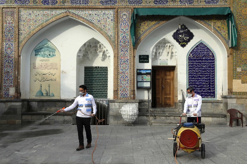 Workers hosing the ground in front of a shrine background