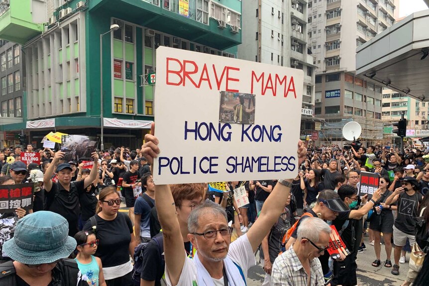 An elderly protester holds a placard which reads "brave mama - Hong Kong police shameless".