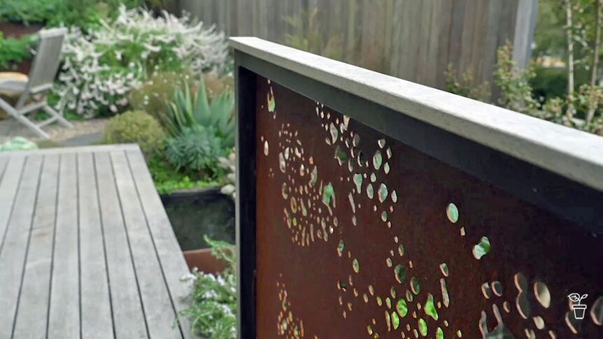 A landscaped garden with a rusted metal feature wall. 