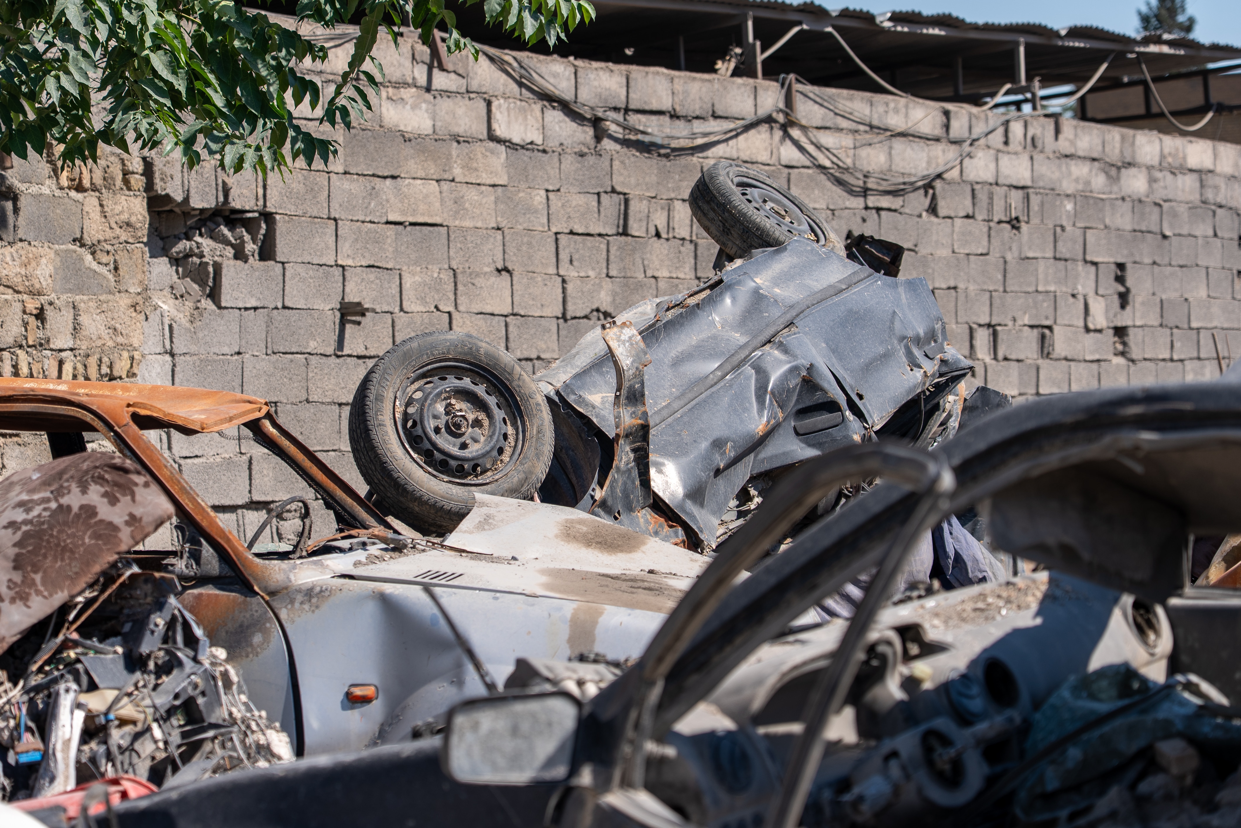 An upside down car with other ruined cars nearby.