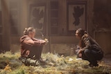 A still image from HBO's The Last of Us, as two characters sit and talk.