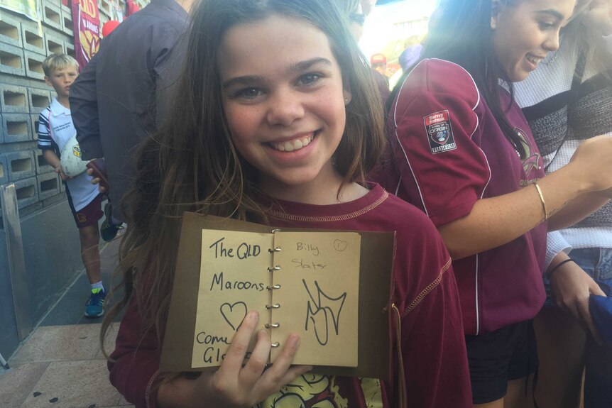 Little girl with big smile holds book with signatures
