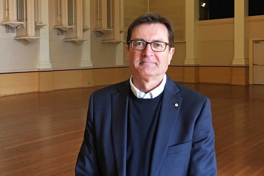 Greg Combet wears a blue suit and a white shirt.