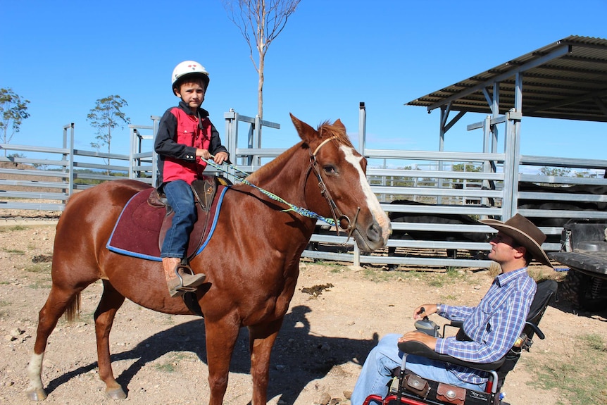 Lawson Cook, 7, sits on his horse next to his dad Rob, who watches on in his wheelchair.