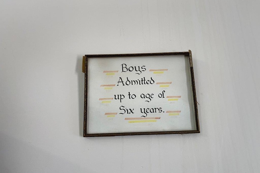 A  wooden-framed sign that reads boys admitted up to the age of six years.