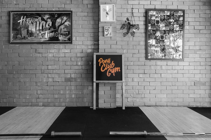 A black and white image of mats and a Pony Club Gym sign.