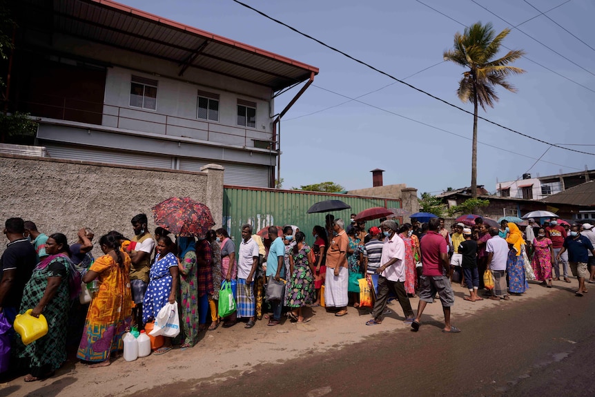 Dozens of people wait in a queue outside a petrol station