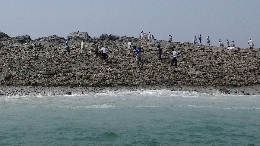 Pakistan men walk on an island that appeared after an earthquake.