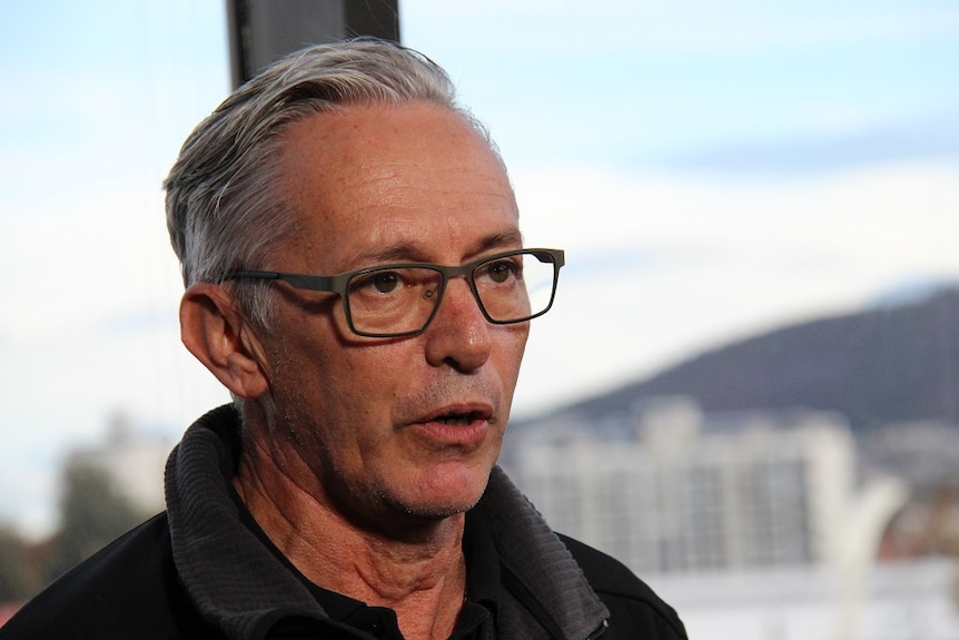 Man with grey hair and glasses looking serious