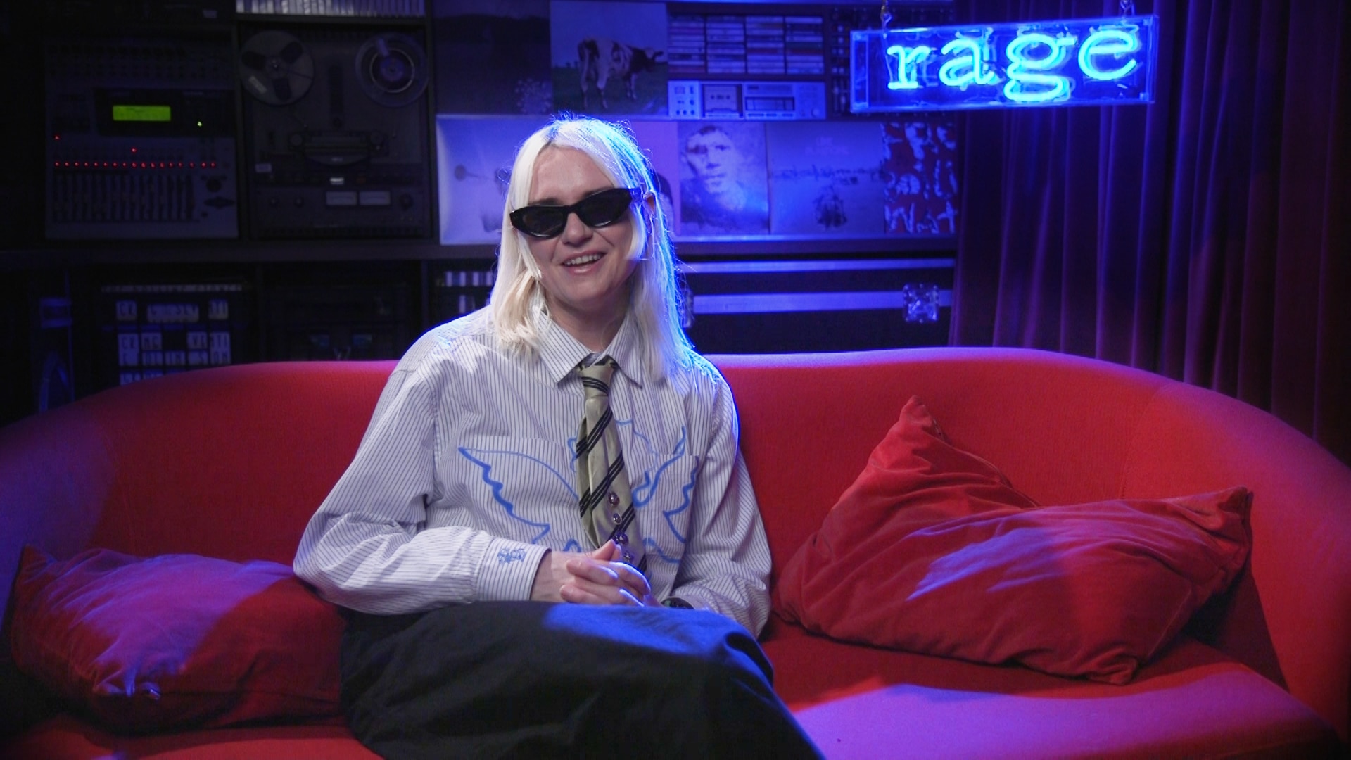 haai wears black sunglasses and sits on a red couch