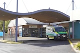 An ambulance sits out the front of a hospital emergency entry.