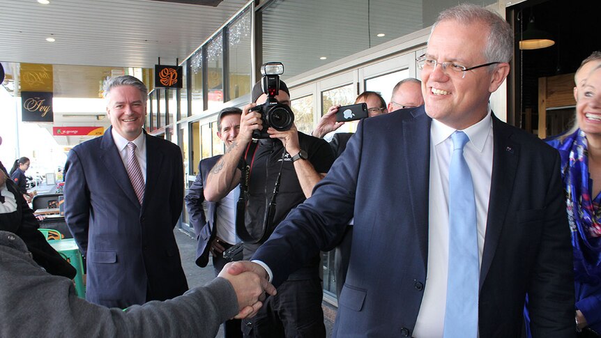 Prime Minister Scott Morrison shakes a hand in Albury as Finance Minister Mathias Cormann looks on.