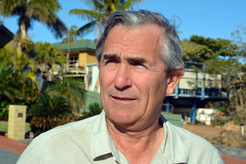 A close-up image of a man wearing a light green shirt with greying hair.