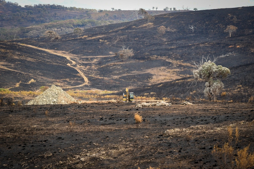 A landscape of burnt hills with a yellow dugout in the middle