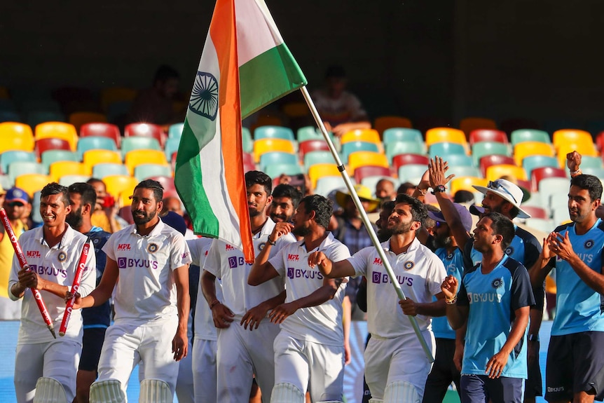 Indian cricketers carry the national flag as they walk around the Gabba after the last Test against Australia.