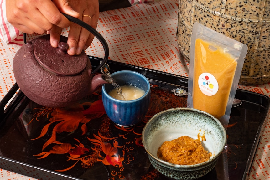 Woman's hands pouring water from a teapot into a cup of miso soup