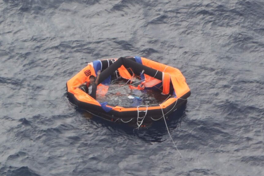 A sailor from the Livestock 1 vessel, which is believed to have sunk in waters off Japan, waves to a rescue aircraft crew.