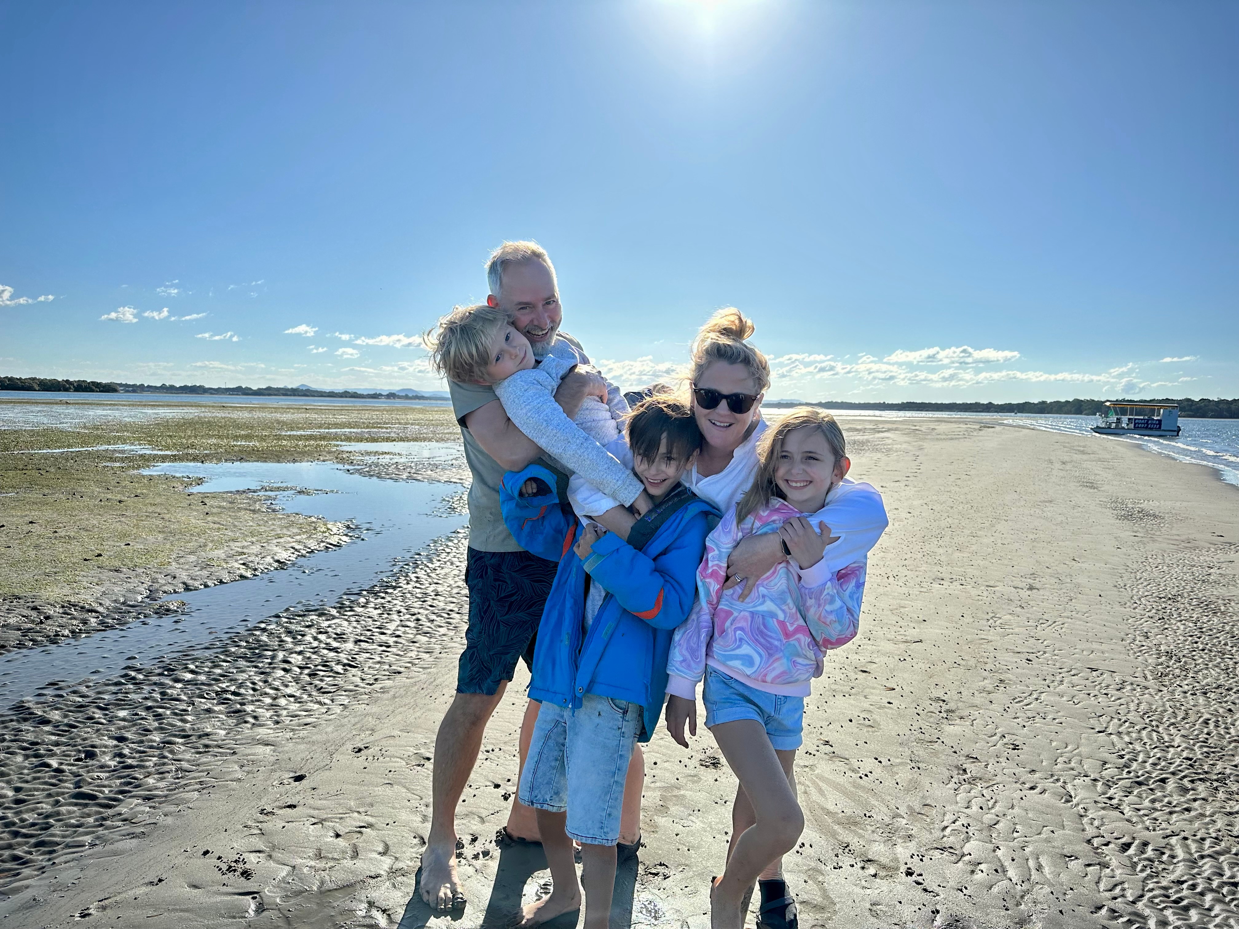 a family of five hugging on the beach