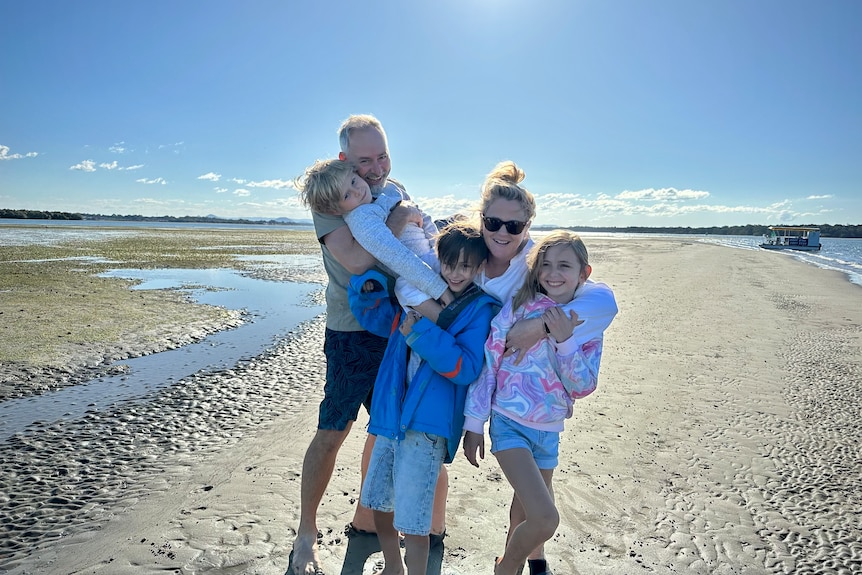 a family of five hugging on the beach
