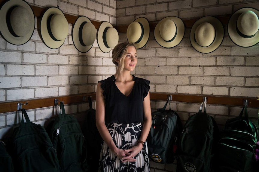 Hannah King a teaching school student stands amongst the school hats and bags outside her class room.