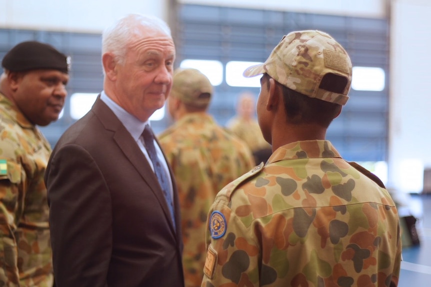 Mid shot of Corrective Services Minister Fran Logan facing a teenage boy in camouflage military uniform