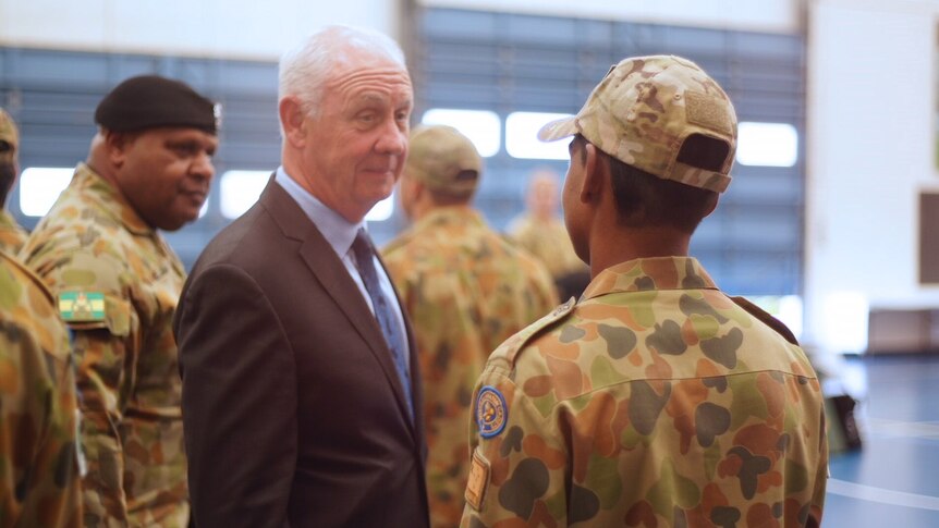 Mid shot of Corrective Services Minister Fran Logan facing a teenage boy in camouflage military uniform