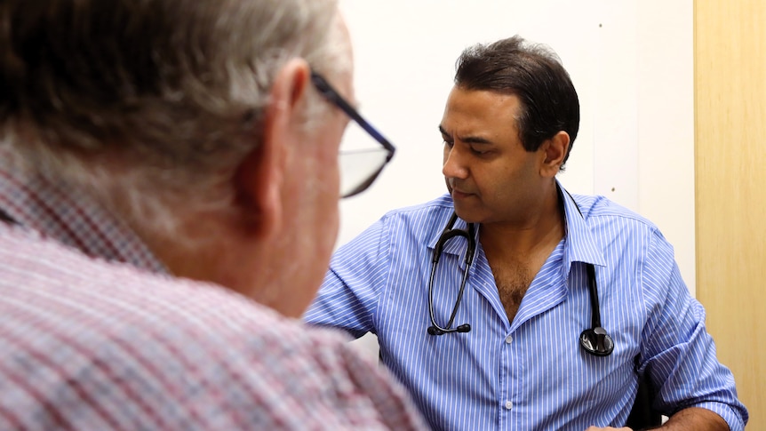 Doctor in back ground, over the shoulder of blurred patient