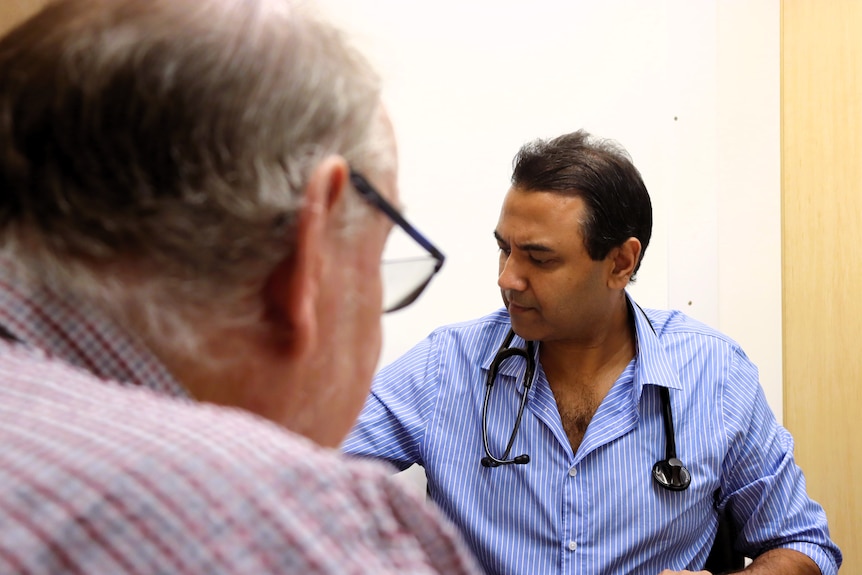 Doctor in back ground, over the shoulder of blurred patient