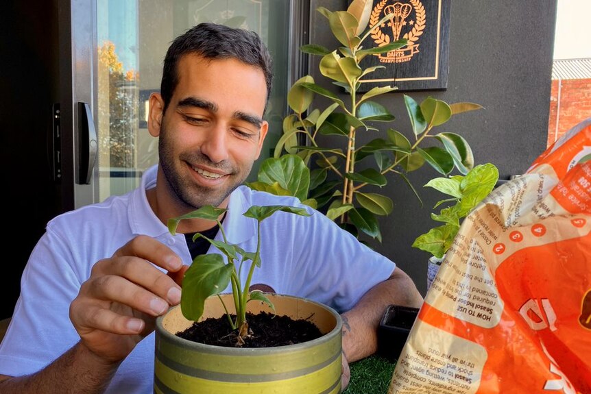 a young man with a plant smiling