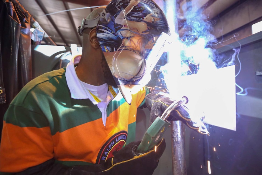 A man in a mask welding metal