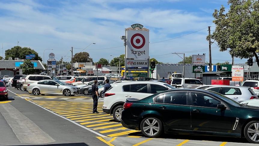 Cars parked in a shopping centre car park, with a Target sign and buildings in the background