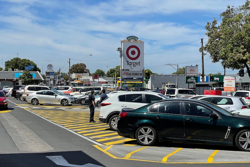 Voitures garées dans un parking d'un centre commercial, avec un panneau Target et des bâtiments en arrière-plan