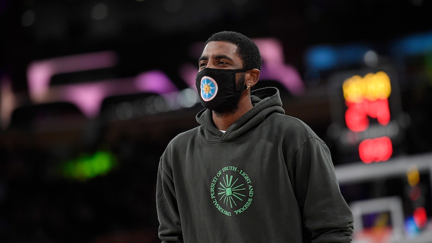 Kyrie Irving wears a mask and a hooded jumper