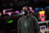 Kyrie Irving wears a mask and a hooded jumper