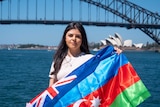 Jessica Oyta carries an Azerbaijan and Australian flag, she is standing in front of the Sydney Harbour Bridge.