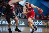 Perth Wildcats player Shawn Redhage drives past Nick Kay of the Illawara Hawks with the basketball in his left hand.