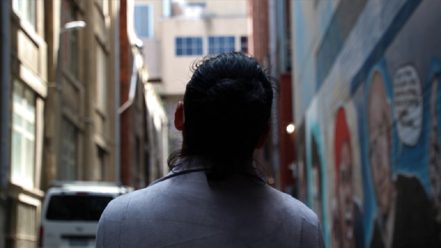 A picture looking down the a Melbourne laneway, with graffiti on one side and the back of a woman in the front of the picture.