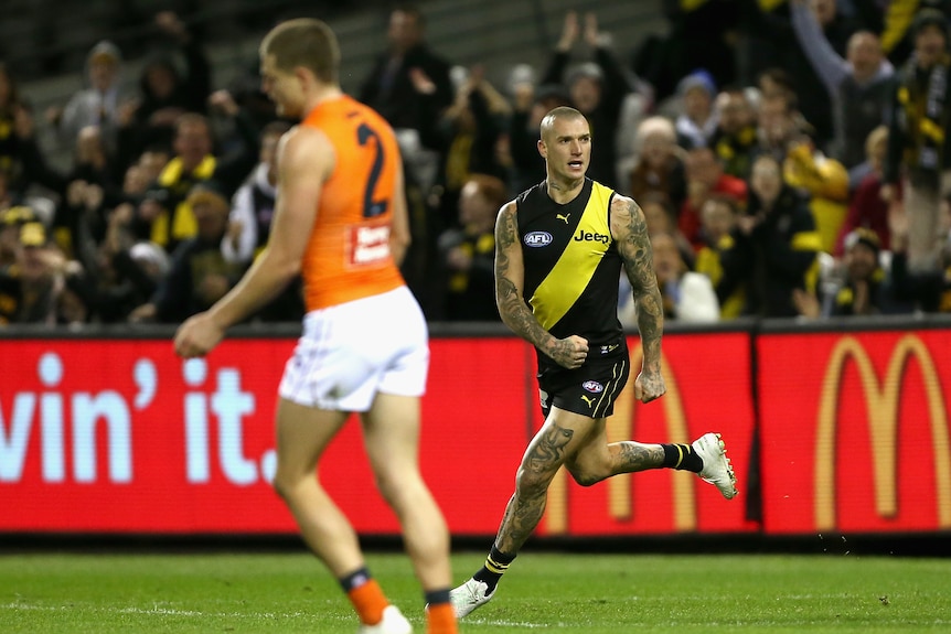 AFL superstar Dustin Martin clenches his fist as he runs away after kicking a goal.