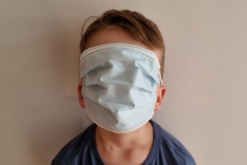 Young boy wearing oversized paper respiratory mask.