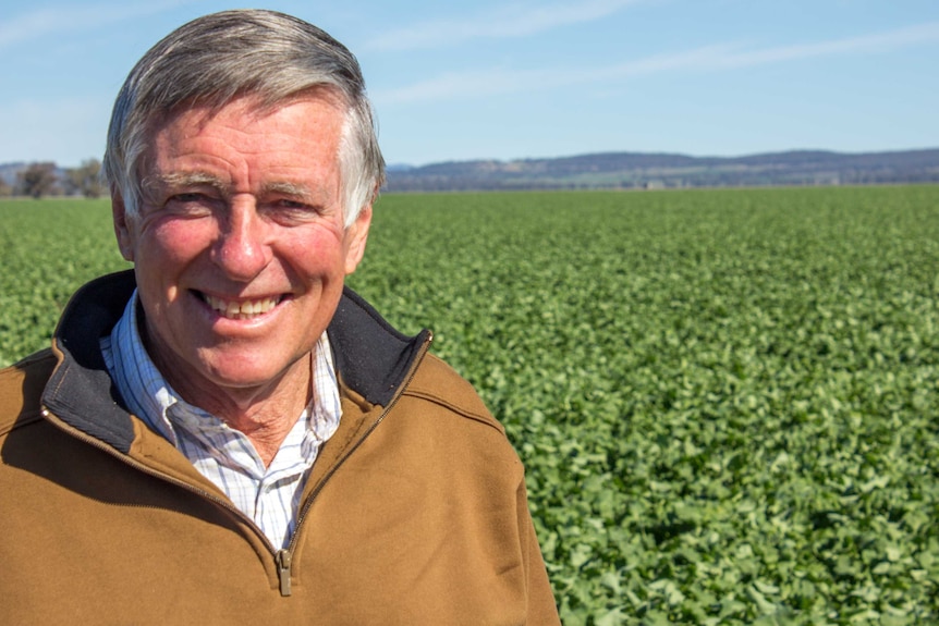 Farmer Sandy Blomfield smiling as he stands in a green paddock.