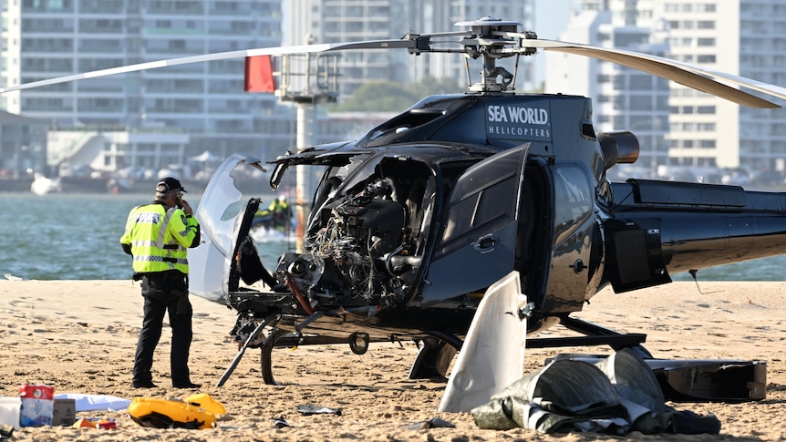 A damaged helicopter on a sandbank.